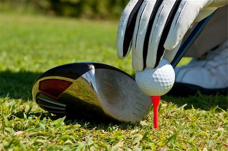 simsearch:400-04942642,k - Hand placing a golf ball on a tee, next to a club. Photographie de stock - Aubaine LD & Abonnement, Code: 400-05690356