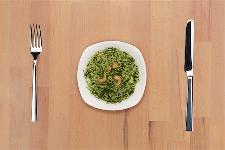 A plate of rice with spinach and cashew nuts on a wooden table with fork and knife. Stock Photo - Budget Royalty-Free & Subscription, Code: 400-05690764