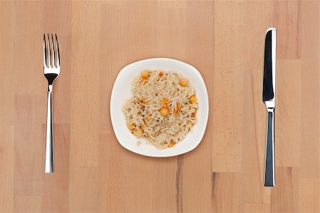 A plate of rice with chickpea and carrot on a wooden table with fork and knife. Stock Photo - Budget Royalty-Free & Subscription, Code: 400-05690762