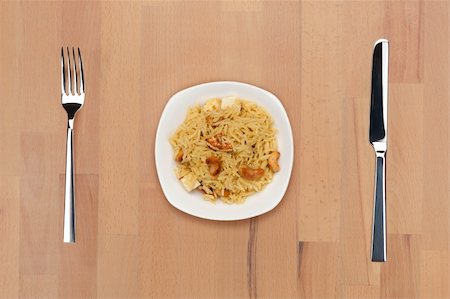 A plate of rice with cashew and cheese on a wooden table with fork and knife. Stock Photo - Budget Royalty-Free & Subscription, Code: 400-05690763