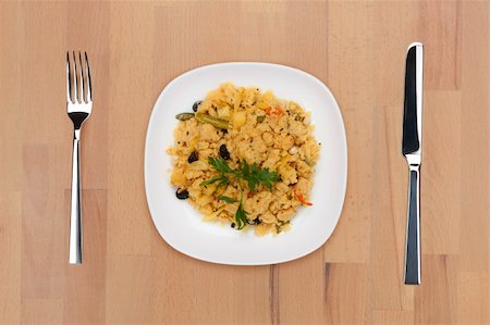 A plate of traditional Indian upma decorated with parsley leaf with fork and knife on a wooden table. Stock Photo - Budget Royalty-Free & Subscription, Code: 400-05690786