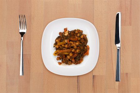 A plate of braised vegetables on a wooden table with fork and knife. Stock Photo - Budget Royalty-Free & Subscription, Code: 400-05690788