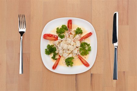 Traditional Indian coconut salad decorated with tomatoes and parsley in a white plate on a wooden table with fork and knife. Stock Photo - Budget Royalty-Free & Subscription, Code: 400-05690789