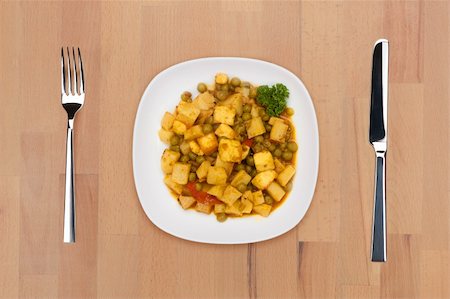 A plate of braised vegetables on a wooden table with fork and knife. Stock Photo - Budget Royalty-Free & Subscription, Code: 400-05690782