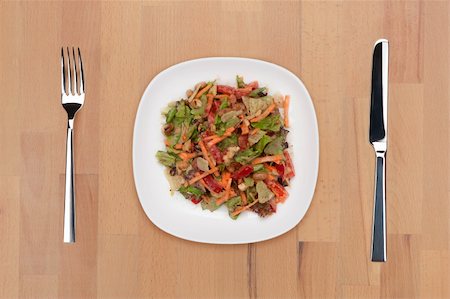 A plate of vegetable salad with fork and knife on a wooden table. Foto de stock - Super Valor sin royalties y Suscripción, Código: 400-05690783