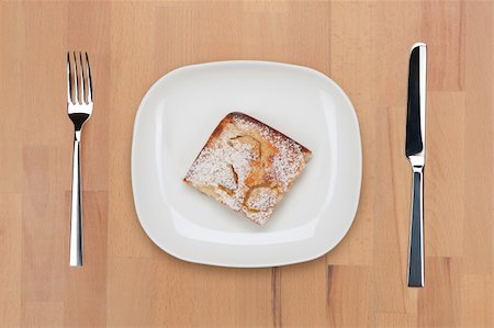 special dessert table - A plate with piece of baked pudding powdered with sugar with fork and knife on a wooden table. Stock Photo - Budget Royalty-Free & Subscription, Code: 400-05690800