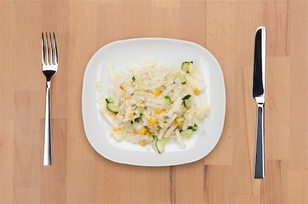 A plate of cabbage salad with cucumber and corn with fork and knife on a wooden table. Stock Photo - Budget Royalty-Free & Subscription, Code: 400-05690803