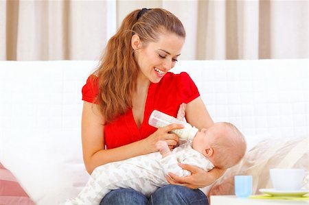 Happy mother sitting on sofa and feeding baby Stock Photo - Budget Royalty-Free & Subscription, Code: 400-05692875
