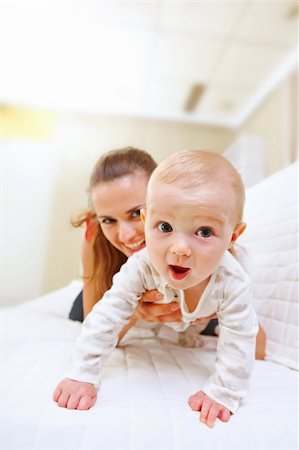 simsearch:400-05899075,k - Happy mother and interested baby playing on divan Fotografie stock - Microstock e Abbonamento, Codice: 400-05692886