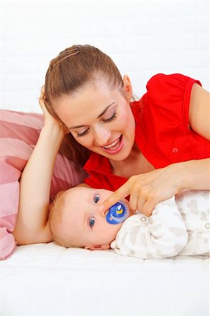 simsearch:400-05899075,k - Young mother laying on couch and playing with baby Fotografie stock - Microstock e Abbonamento, Codice: 400-05692880