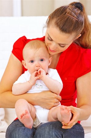 simsearch:400-05899075,k - Baby putting his hands in mouth while sitting on mother laps Fotografie stock - Microstock e Abbonamento, Codice: 400-05692898