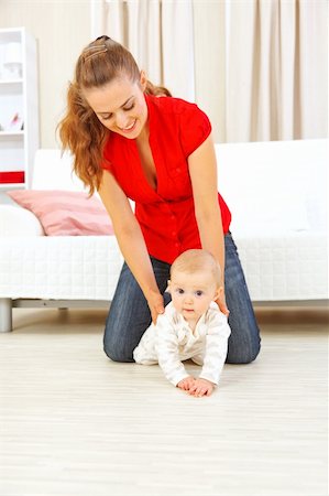 simsearch:400-05750410,k - Smiling mother helping cheerful baby learn to creep Photographie de stock - Aubaine LD & Abonnement, Code: 400-05692893