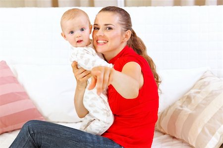 simsearch:400-05899075,k - Happy mother sitting on divan and showing something to her baby Fotografie stock - Microstock e Abbonamento, Codice: 400-05692951