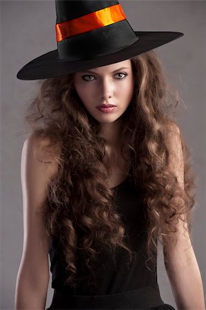 face shot of a young and beautiful girl dressed up for halloween with a huge black witch hat looking straight into the cam Stock Photo - Budget Royalty-Free & Subscription, Code: 400-05693468