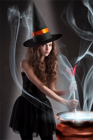 halloween shot of a young and beautiful witch wearing a huge black and orange hat making a poison in a big pot Stock Photo - Budget Royalty-Free & Subscription, Code: 400-05693470