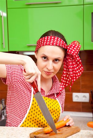 retro wife cooking - Serious woman in the kitchen is cutting a fresh carrot Stock Photo - Budget Royalty-Free & Subscription, Code: 400-05705200