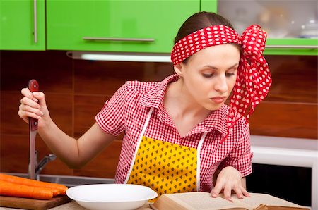 Serious woman in the kitchen with knofe is reading recipe book Stock Photo - Budget Royalty-Free & Subscription, Code: 400-05705201