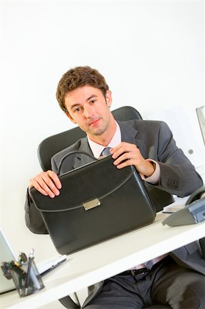 Confident modern businessman sitting at office desk with briefcase Stock Photo - Budget Royalty-Free & Subscription, Code: 400-05708328