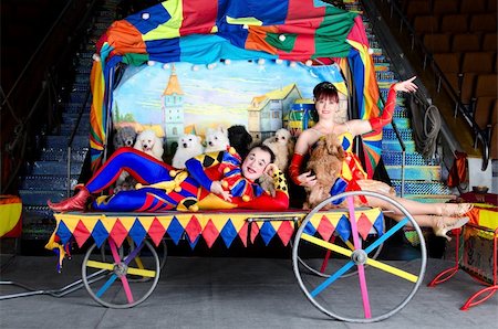 Couple of smiling clowns posing with small dogs on vintage carriage with the painting of the old town Stock Photo - Budget Royalty-Free & Subscription, Code: 400-05700766