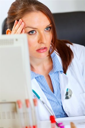 simsearch:400-07519214,k - Concerned female doctor sitting at office table and holding hand near head Stock Photo - Budget Royalty-Free & Subscription, Code: 400-05701707