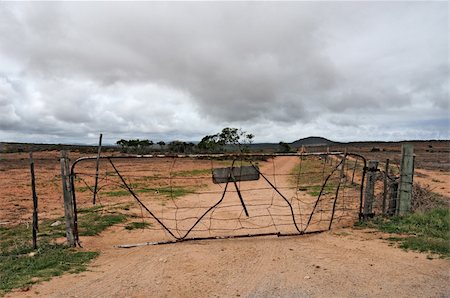 Rusted farm gate on a dusty farm road against dark sky Photographie de stock - Aubaine LD & Abonnement, Code: 400-05701904