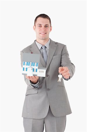 simsearch:400-07420953,k - Portrait of a smiling businessman showing a miniature house and keys against a white background Stock Photo - Budget Royalty-Free & Subscription, Code: 400-05714895