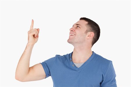 finger pointing up - Smiling man pointing at something against a white background Stock Photo - Budget Royalty-Free & Subscription, Code: 400-05715246