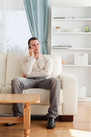 simsearch:6109-06195006,k - Portrait of a man on the phone while sitting on his sofa in his living room Foto de stock - Super Valor sin royalties y Suscripción, Código: 400-05715319