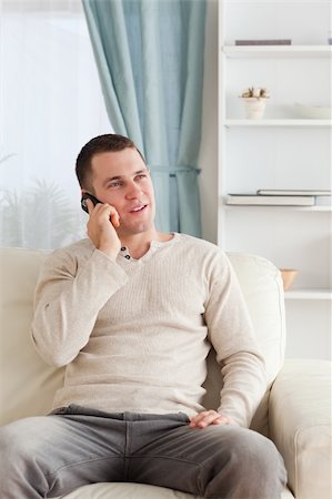 simsearch:6109-06195006,k - Portrait of a young man on the phone while sitting on his sofa in his living room Foto de stock - Super Valor sin royalties y Suscripción, Código: 400-05715320