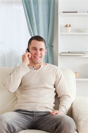 simsearch:6109-06195006,k - Portrait of a young man on the phone while sitting on his couch in his living room Foto de stock - Super Valor sin royalties y Suscripción, Código: 400-05715321