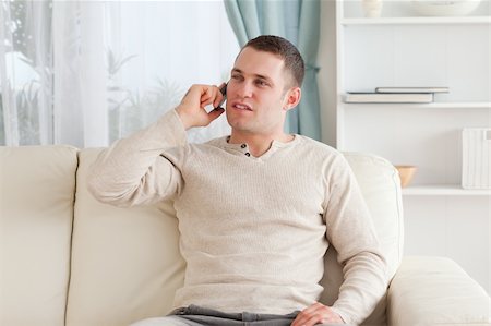 simsearch:6109-06195006,k - Young man on the phone while sitting on his couch in his living room Foto de stock - Super Valor sin royalties y Suscripción, Código: 400-05715322