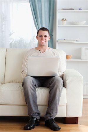simsearch:400-05715585,k - Portrait of a man using a laptop while sitting on a sofa in his living room Foto de stock - Super Valor sin royalties y Suscripción, Código: 400-05715526