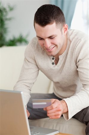 face card - Portrait of a man using a laptop to book a flight in his living room Foto de stock - Super Valor sin royalties y Suscripción, Código: 400-05715569