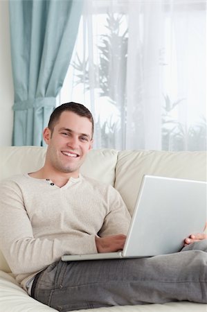 simsearch:400-05715585,k - Portrait of a smiling man relaxing with a laptop in his living room Foto de stock - Super Valor sin royalties y Suscripción, Código: 400-05715588