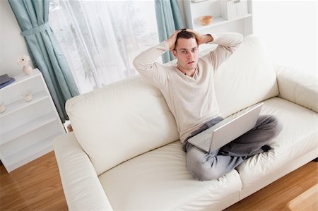 simsearch:400-05715585,k - Sad man relaxing with a notebook in his living room Foto de stock - Super Valor sin royalties y Suscripción, Código: 400-05715597