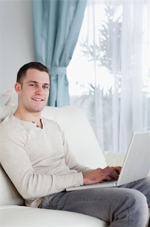 simsearch:400-05715585,k - Portrait of a happy man typing on his notebook in his living room Foto de stock - Super Valor sin royalties y Suscripción, Código: 400-05715609
