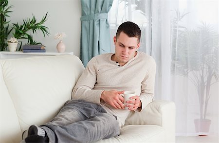 Sad man holding a cup of coffee in his living room Stock Photo - Budget Royalty-Free & Subscription, Code: 400-05715630