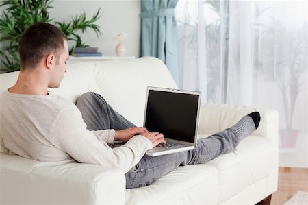 simsearch:400-05715585,k - Man lying on his couch using a laptop in his living room Foto de stock - Super Valor sin royalties y Suscripción, Código: 400-05715643