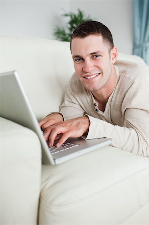 simsearch:400-05715585,k - Portrait of a smiling man lying on a couch with a laptop in his living room Foto de stock - Super Valor sin royalties y Suscripción, Código: 400-05715662