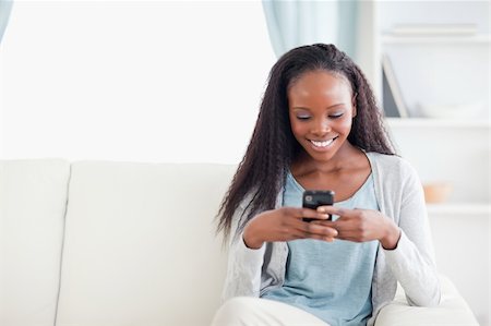 simsearch:400-05716936,k - Smiling woman in living room reading text message Stock Photo - Budget Royalty-Free & Subscription, Code: 400-05716428