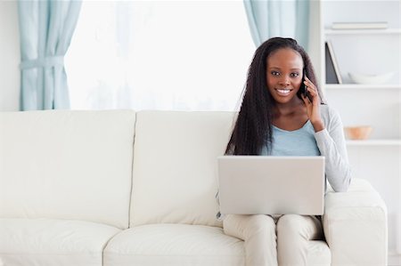 simsearch:400-05716936,k - Smiling woman with laptop and mobile phone on the sofa Stock Photo - Budget Royalty-Free & Subscription, Code: 400-05716434