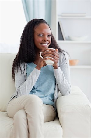 simsearch:400-05716909,k - Smiling woman on sofa with a cup Stock Photo - Budget Royalty-Free & Subscription, Code: 400-05716499