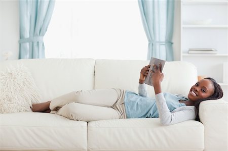 simsearch:400-05716909,k - Smiling woman lying on couch reading Stock Photo - Budget Royalty-Free & Subscription, Code: 400-05716939