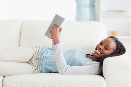 simsearch:400-05716909,k - Smiling woman lying on couch reading a novel Stock Photo - Budget Royalty-Free & Subscription, Code: 400-05716943