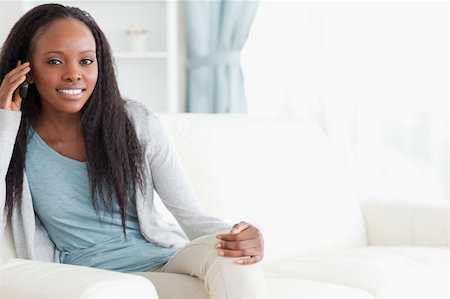 simsearch:400-05716936,k - Smiling woman sitting on sofa while using her phone Stock Photo - Budget Royalty-Free & Subscription, Code: 400-05717087