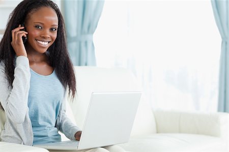 simsearch:400-05716936,k - Smiling young woman on the phone while working on laptop Stock Photo - Budget Royalty-Free & Subscription, Code: 400-05717081