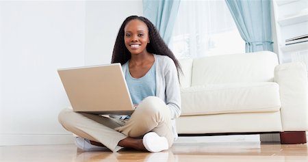 Smiling woman sitting on the floor using her laptop Stock Photo - Budget Royalty-Free & Subscription, Code: 400-05717160