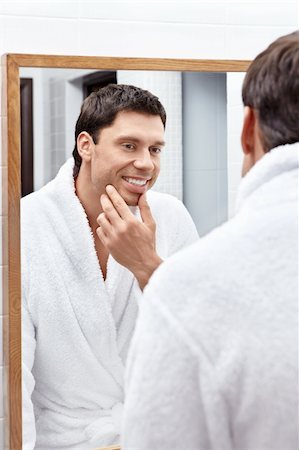 The young man looks in the mirror in the bathroom Stock Photo - Budget Royalty-Free & Subscription, Code: 400-05717390