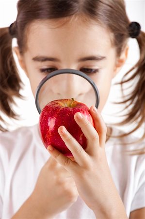 Little girl with a magnifying glass inspecting microbes on a red apple Stock Photo - Budget Royalty-Free & Subscription, Code: 400-05717525