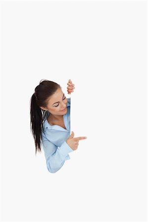 simsearch:400-05718227,k - Businesswoman looking around the corner while pointing against a white background Stock Photo - Budget Royalty-Free & Subscription, Code: 400-05718224